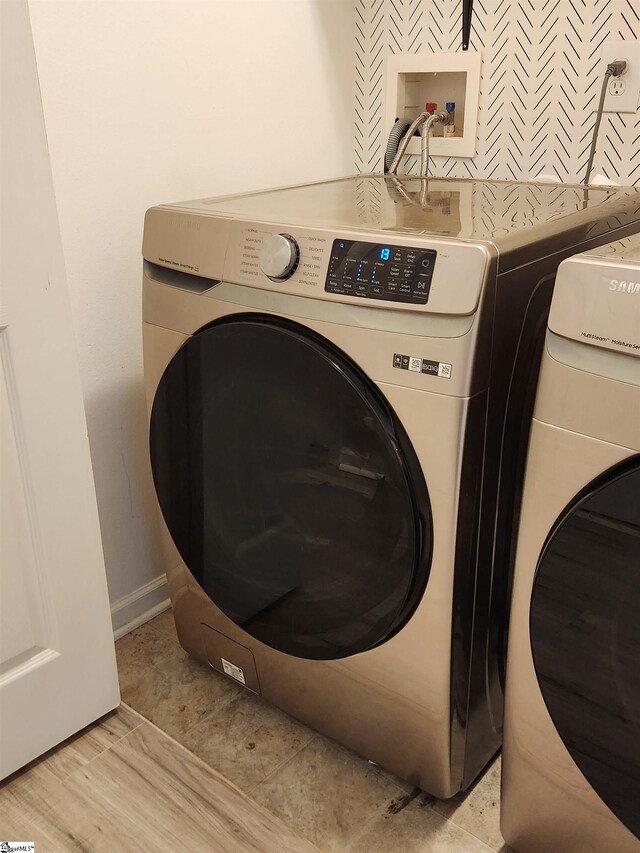 clothes washing area with independent washer and dryer and baseboards