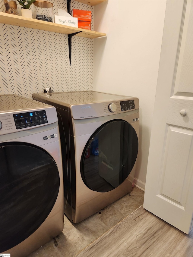 clothes washing area featuring washing machine and clothes dryer, light wood-style flooring, and baseboards