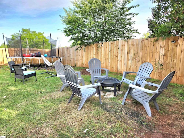 view of yard featuring a trampoline and an outdoor fire pit