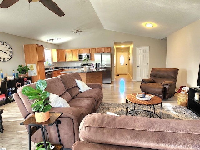 living room with light wood-type flooring, vaulted ceiling, and ceiling fan