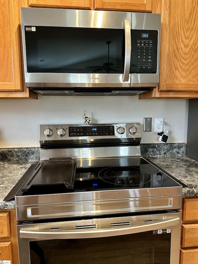 kitchen view of stainless steel appliances, dark countertops, and brown cabinetry