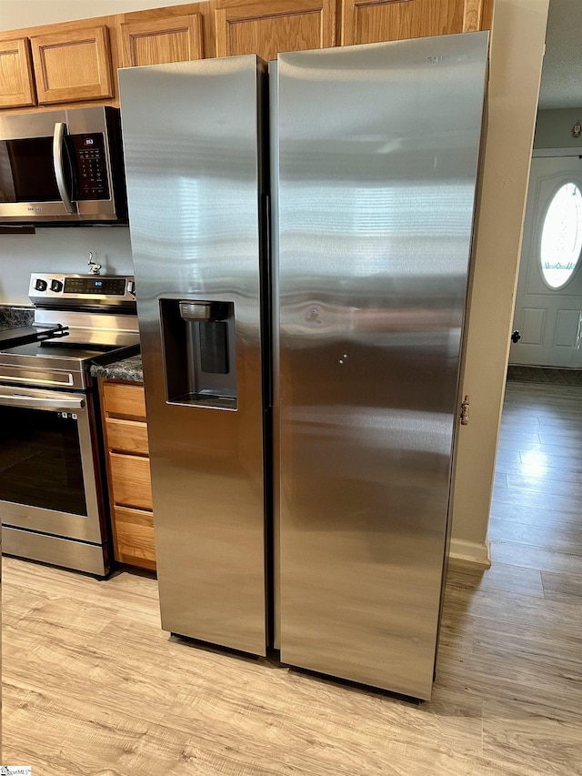 kitchen featuring appliances with stainless steel finishes, light wood-style flooring, and brown cabinets