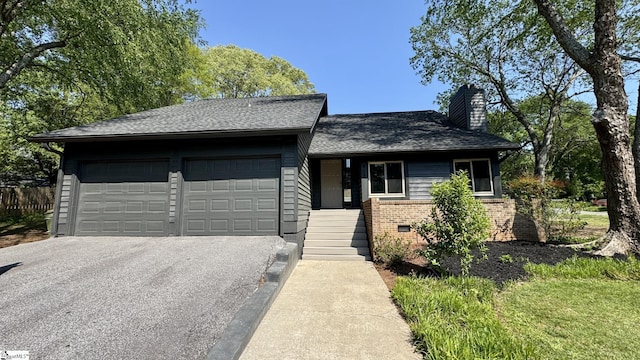 view of front of house with a garage, asphalt driveway, a chimney, brick siding, and roof with shingles
