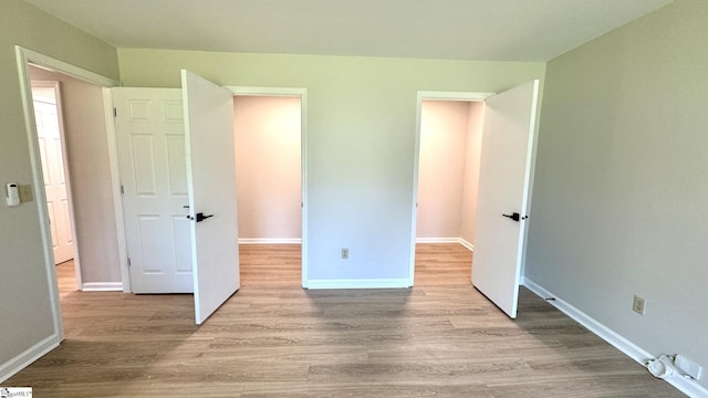 unfurnished bedroom with wood finished floors and baseboards