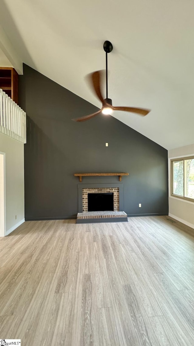 unfurnished living room featuring vaulted ceiling, ceiling fan, wood finished floors, baseboards, and a fireplace