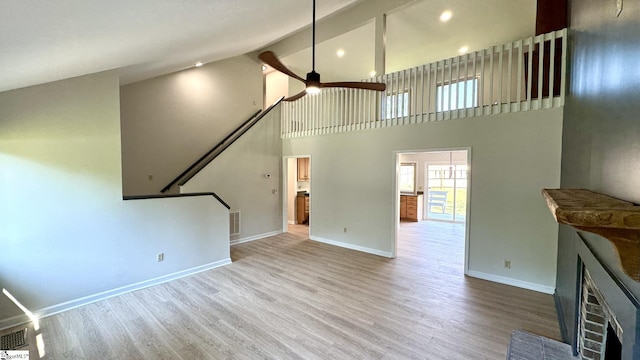 unfurnished living room with a fireplace, ceiling fan, high vaulted ceiling, baseboards, and wood finished floors