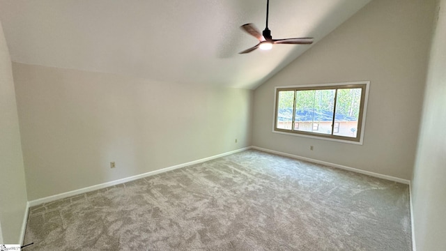 carpeted empty room featuring a ceiling fan, vaulted ceiling, and baseboards