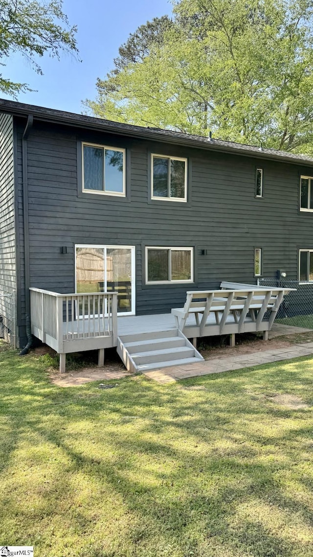 rear view of house featuring a lawn and a wooden deck