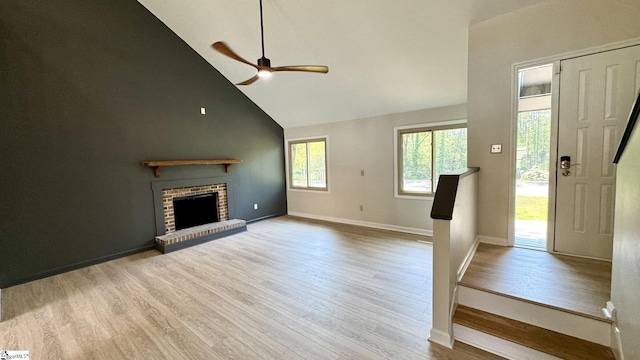unfurnished living room with high vaulted ceiling, wood finished floors, a ceiling fan, a fireplace, and baseboards
