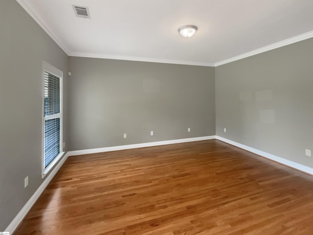 empty room featuring ornamental molding, baseboards, and wood finished floors