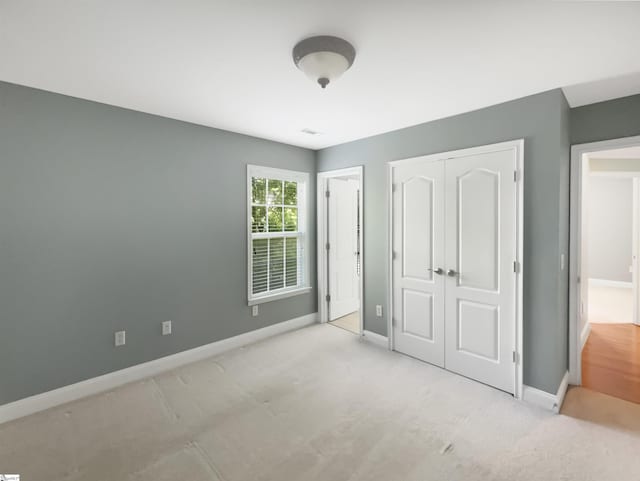 unfurnished bedroom with baseboards, carpet floors, and a closet