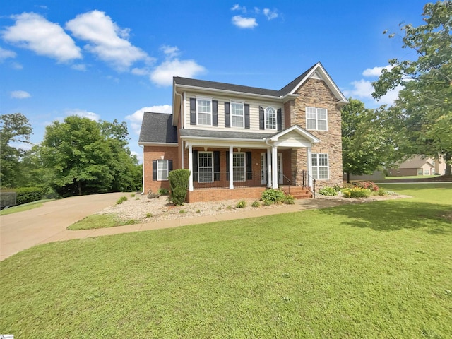 view of front of house with a front lawn, a porch, stone siding, concrete driveway, and brick siding