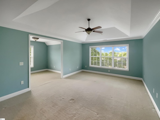 carpeted spare room with a ceiling fan, baseboards, a tray ceiling, and crown molding