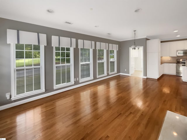 unfurnished living room with a chandelier, dark wood-style floors, baseboards, and recessed lighting