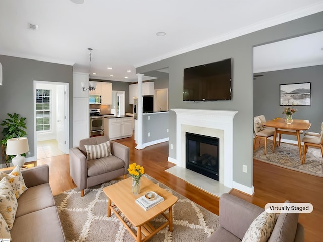 living area featuring wood finished floors, ornamental molding, baseboards, a fireplace with flush hearth, and recessed lighting