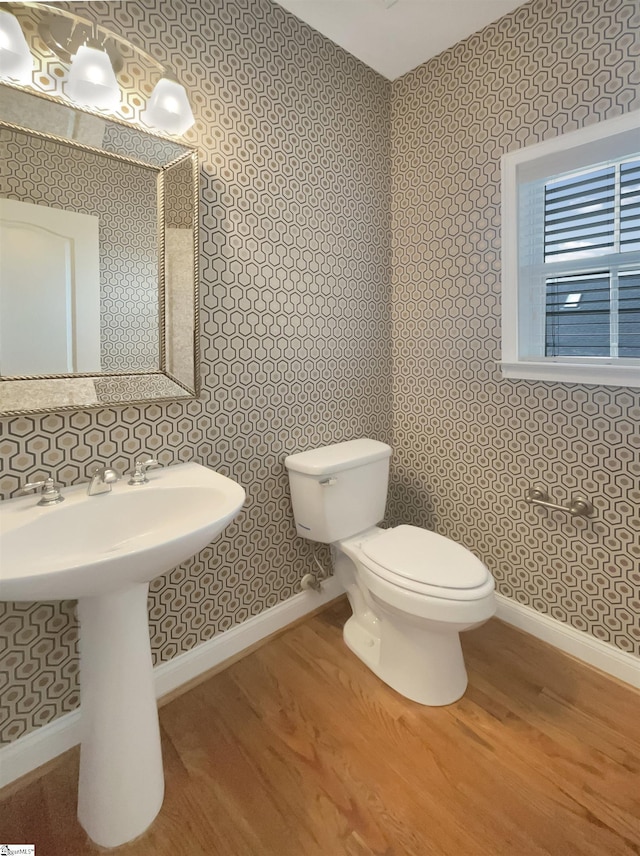 bathroom featuring wallpapered walls, wood finished floors, baseboards, and toilet