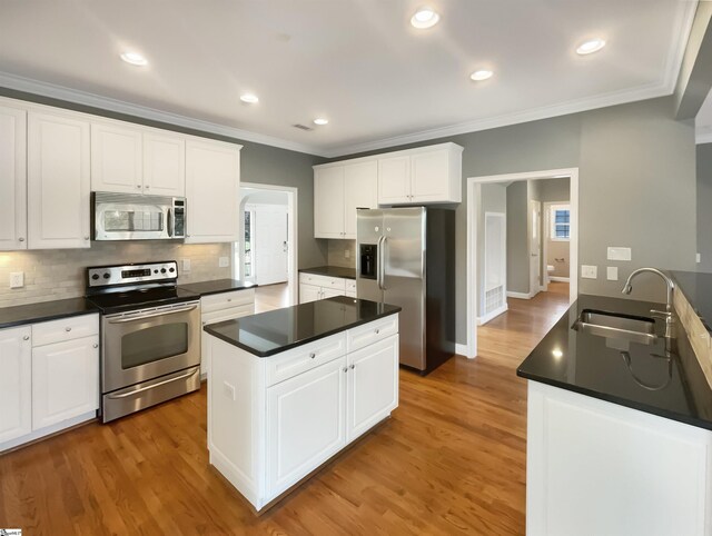 kitchen with stainless steel appliances, a sink, dark countertops, crown molding, and tasteful backsplash