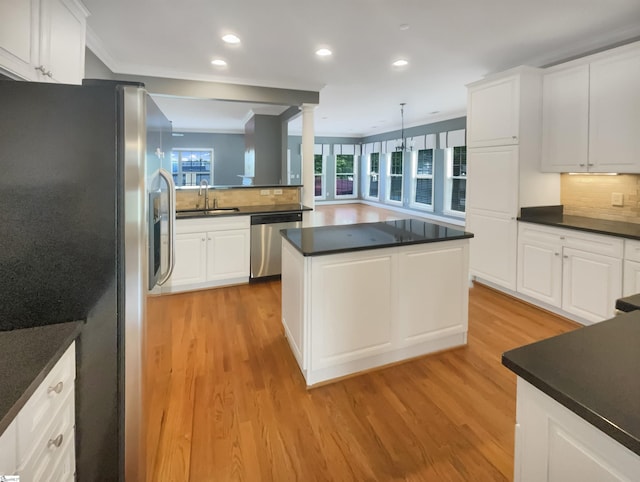 kitchen featuring stainless steel appliances, a sink, dark countertops, light wood-style floors, and recessed lighting