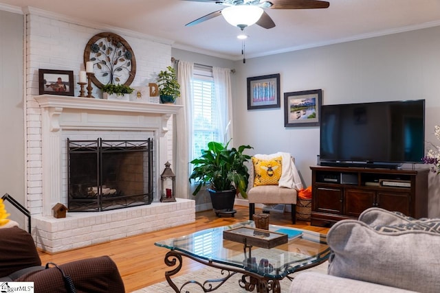 living room with wood finished floors, ornamental molding, ceiling fan, and a fireplace