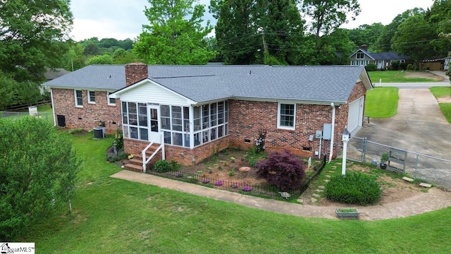 rear view of house with a sunroom, cooling unit, roof with shingles, a chimney, and brick siding