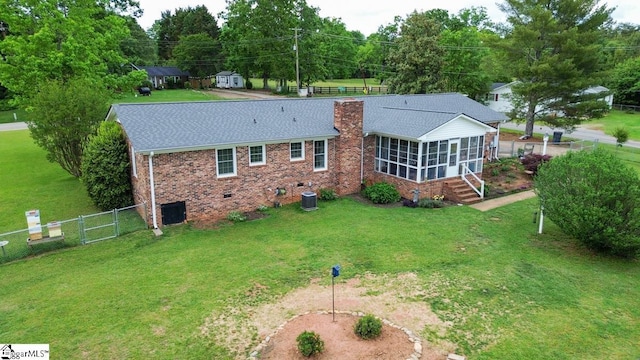 rear view of property with a sunroom, a chimney, brick siding, a shingled roof, and central AC unit