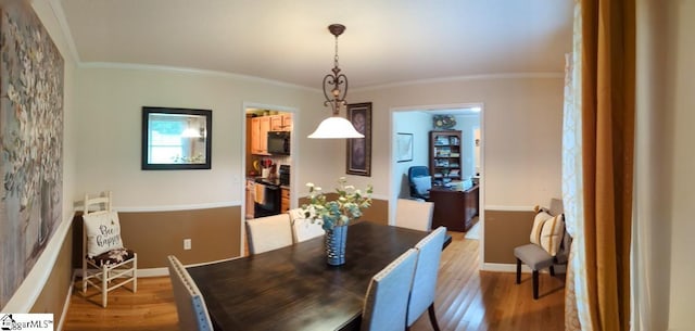 dining space with light wood-style floors, ornamental molding, and baseboards