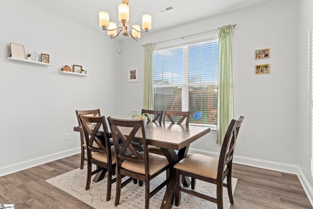 dining space featuring a chandelier, wood finished floors, and baseboards