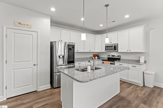 kitchen with stainless steel appliances, a sink, wood finished floors, white cabinets, and recessed lighting