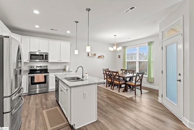kitchen featuring appliances with stainless steel finishes, a sink, light wood-style flooring, recessed lighting, and white cabinets