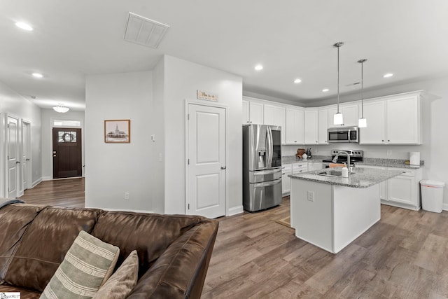 kitchen featuring stainless steel appliances, a sink, recessed lighting, light wood-style flooring, and light stone counters