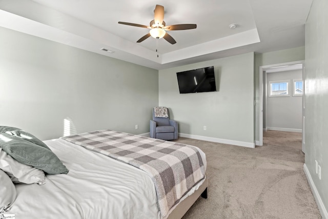 carpeted bedroom featuring baseboards, a raised ceiling, and ceiling fan