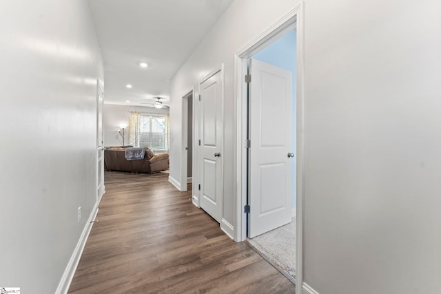 hallway featuring wood finished floors, baseboards, and recessed lighting