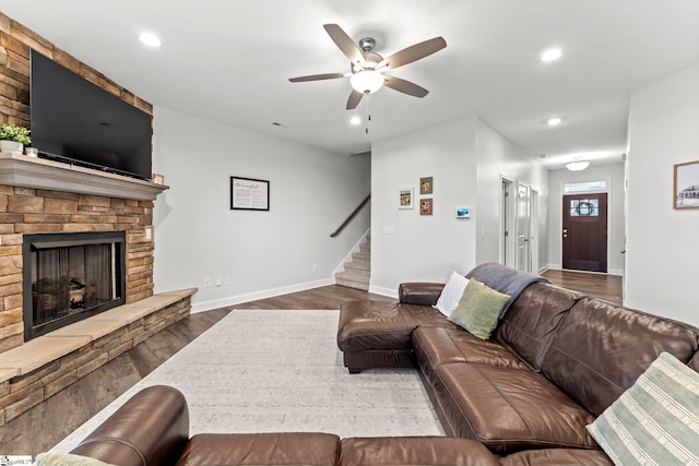 living room featuring wood finished floors, stairway, a ceiling fan, recessed lighting, and a stone fireplace