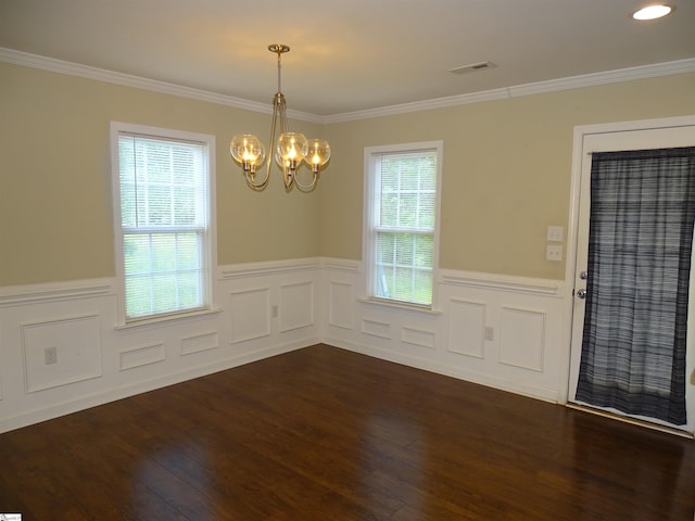 spare room featuring a chandelier, wainscoting, ornamental molding, dark wood-style flooring, and a decorative wall