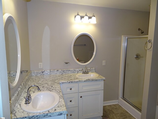 bathroom with a stall shower, double vanity, and baseboards