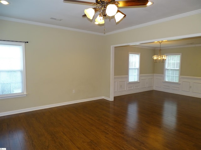 empty room featuring a chandelier, dark wood finished floors, plenty of natural light, a ceiling fan, and wainscoting