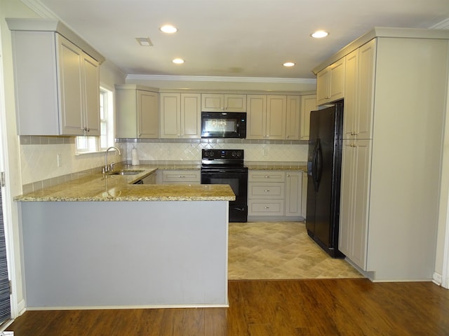 kitchen with black appliances, a sink, a peninsula, light stone countertops, and light wood-style floors