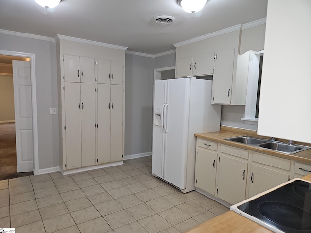 kitchen featuring a sink, ornamental molding, baseboards, white cabinetry, and light tile patterned flooring