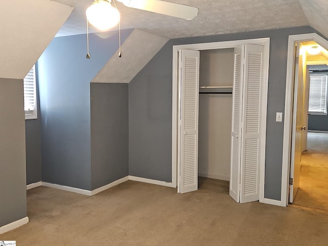 unfurnished bedroom with carpet flooring, a closet, lofted ceiling, baseboards, and ceiling fan