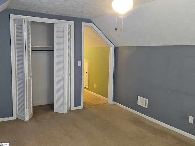 unfurnished bedroom featuring lofted ceiling, carpet floors, a closet, and baseboards