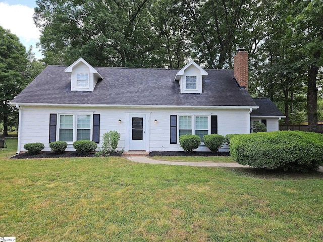 cape cod-style house with a front lawn, a chimney, and roof with shingles