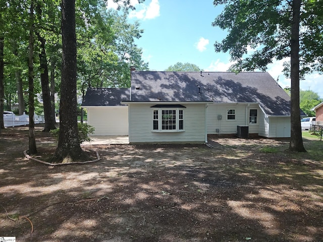 back of house featuring central air condition unit and a shingled roof
