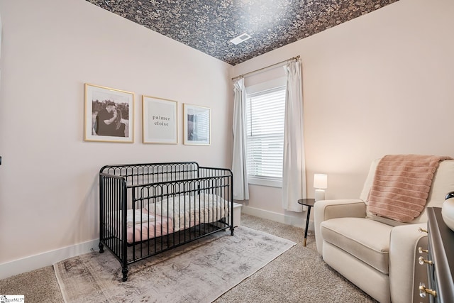 carpeted bedroom with baseboards and a crib
