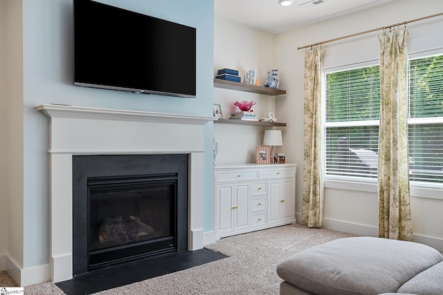 living area with carpet flooring, a fireplace with flush hearth, and baseboards