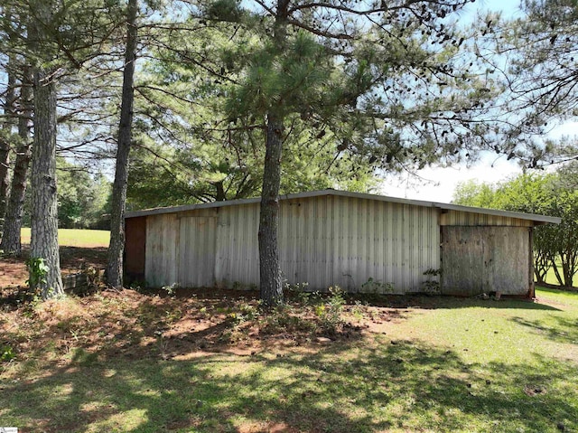 view of home's exterior with board and batten siding, an outbuilding, and a yard