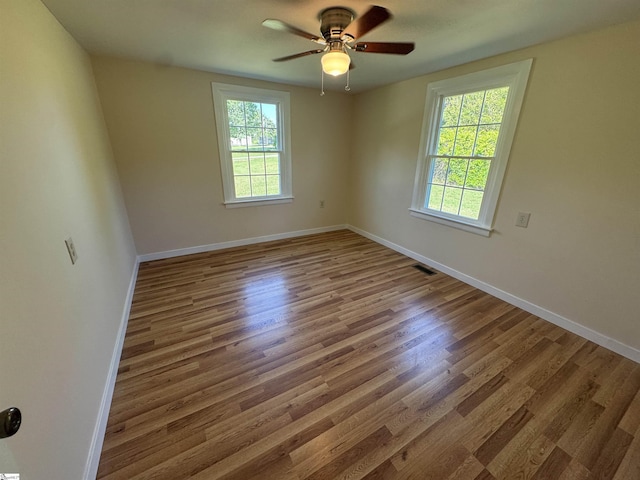 unfurnished room with wood finished floors, a ceiling fan, and baseboards