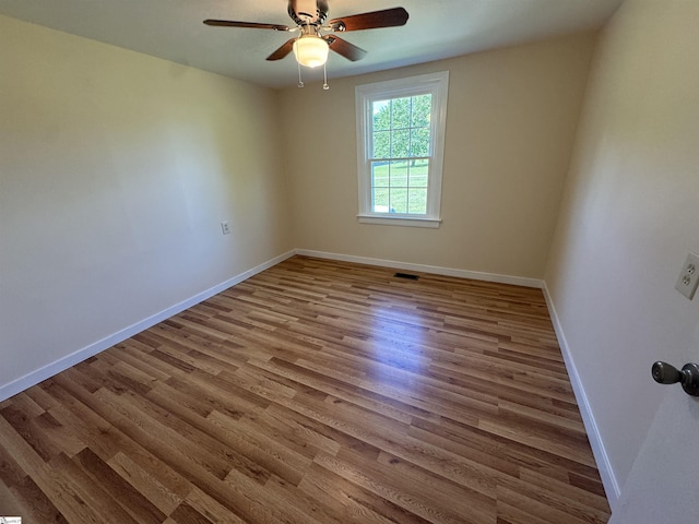 spare room featuring a ceiling fan, wood finished floors, and baseboards