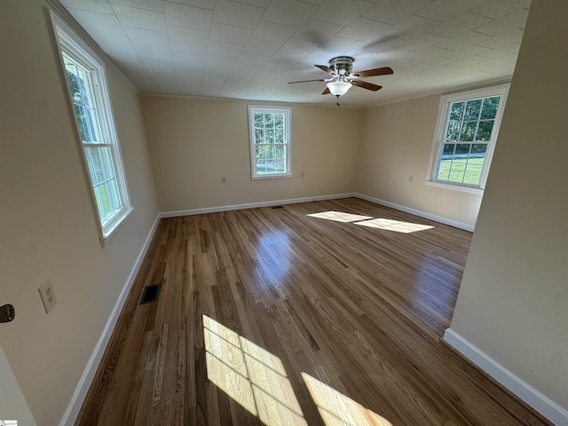 unfurnished room with wood finished floors, ceiling fan, baseboards, and crown molding