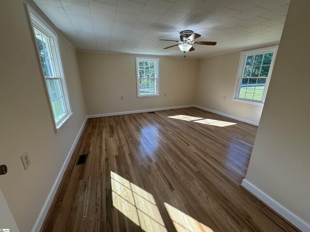 empty room with wood finished floors, baseboards, a ceiling fan, and ornamental molding