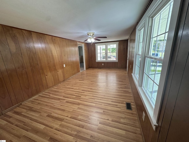 spare room with wood finished floors, wooden walls, and ceiling fan